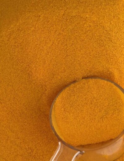 Glastasse gefüllt mit feinem orangegoldenem Pulver auf gleichfarbigem Untergrund aus demselben Pulvermaterial